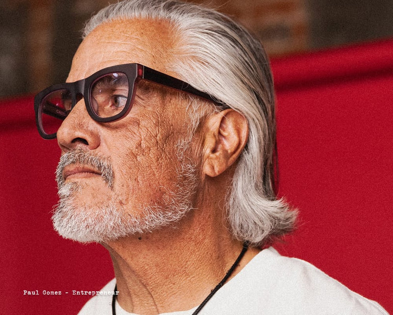 Man with gray hair and glasses against a red background